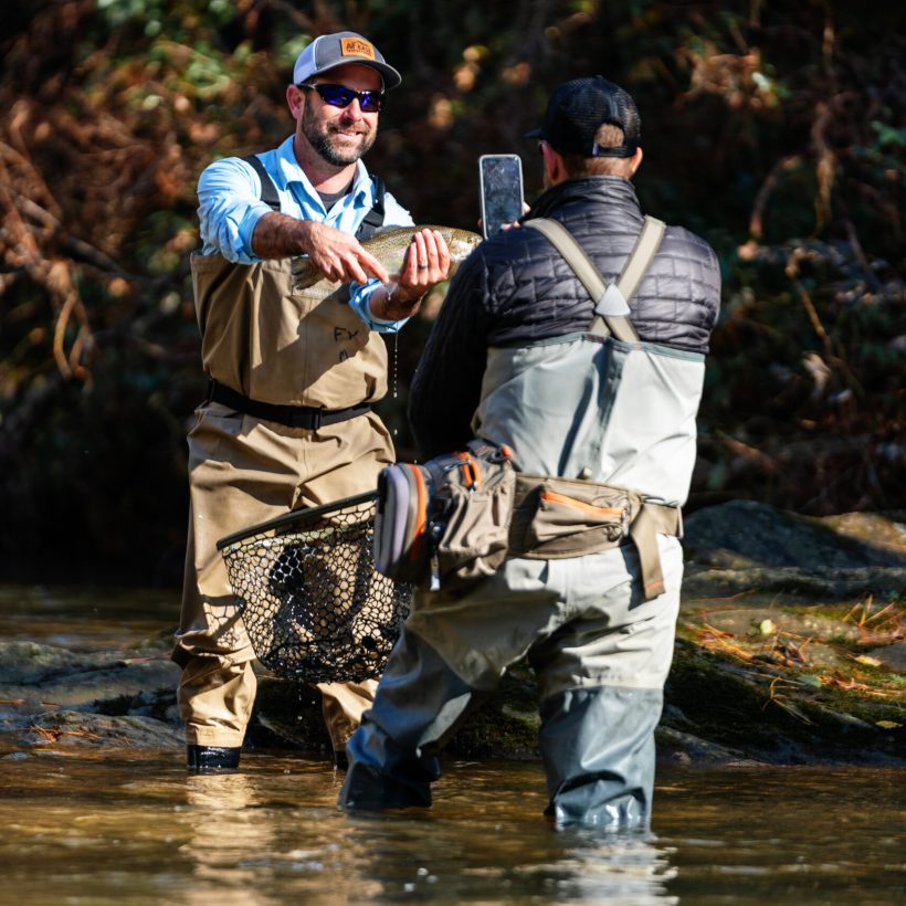 fly fisherman posing for a picture with his catch